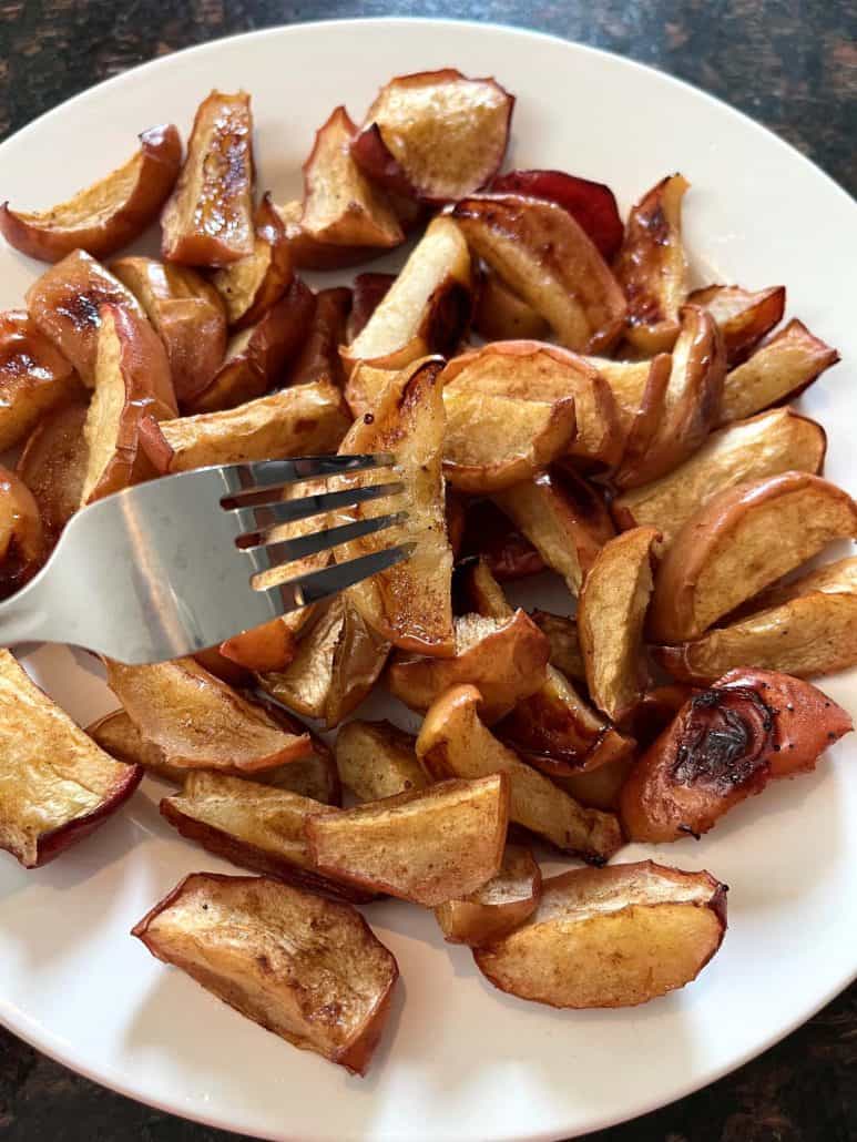 Top view of roasted apples on a plate with a fork.