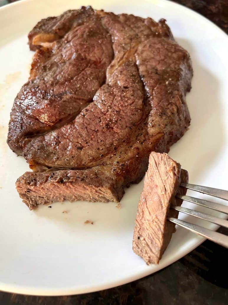 Sliced boneless chuck steak on a white plate, showing its juicy and tender interior after being perfectly cooked in the air fryer.