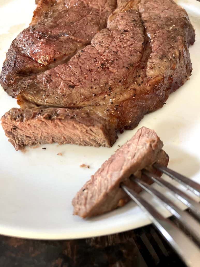 Close-up of sliced boneless chuck steak on a plate, revealing a tender and juicy interior, freshly cooked in the air fryer.