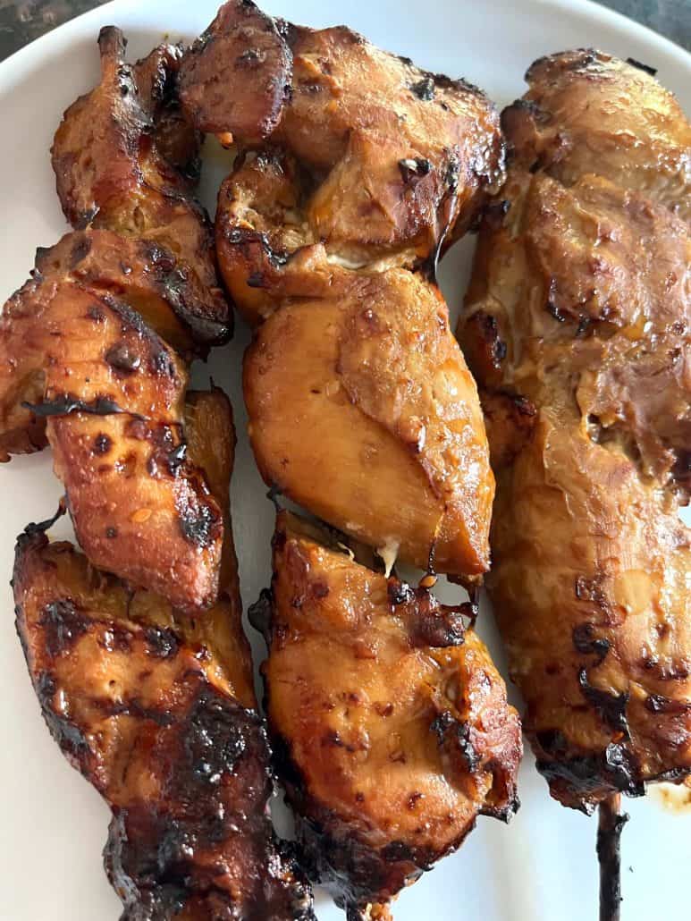 Zoom-in of three pieces air fryer chicken teriyaki skewers on a white plate. 