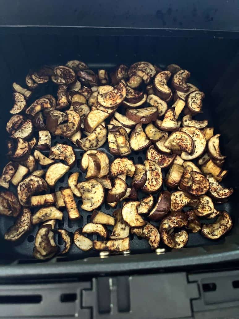 Close-up of an air fryer basket filled with crispy, roasted Chinese eggplant chunks, showcasing the final cooked dish ready to be served.