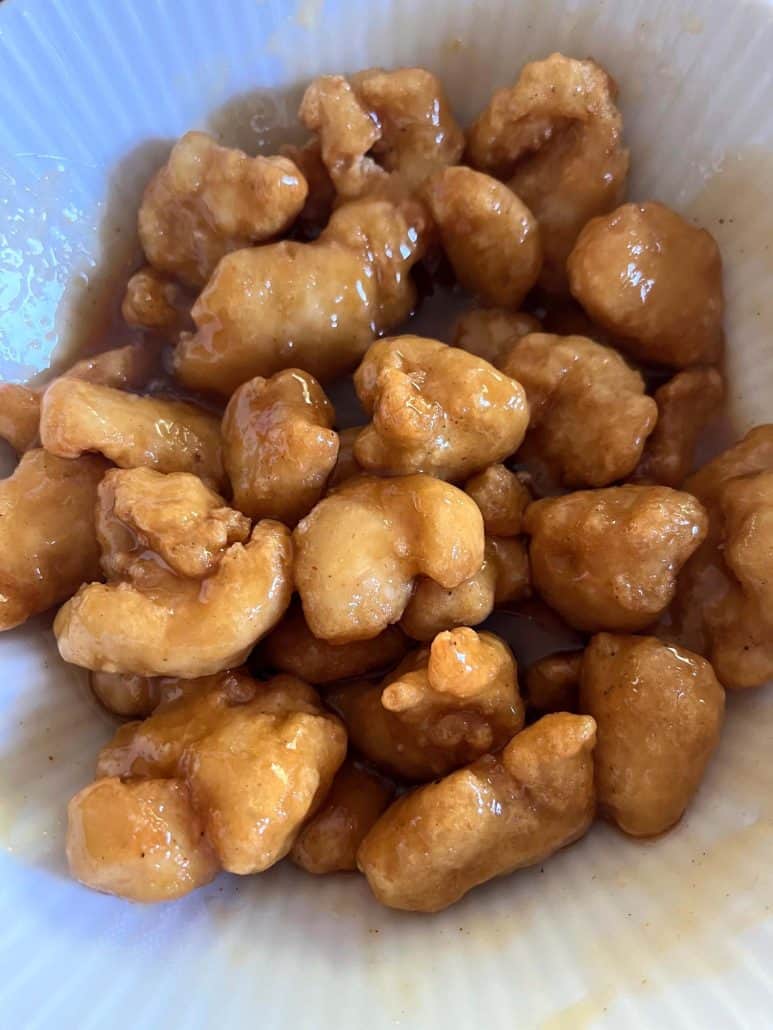 Orange Chicken in a bowl, coated with a sweet and tangy orange sauce, ready to serve.