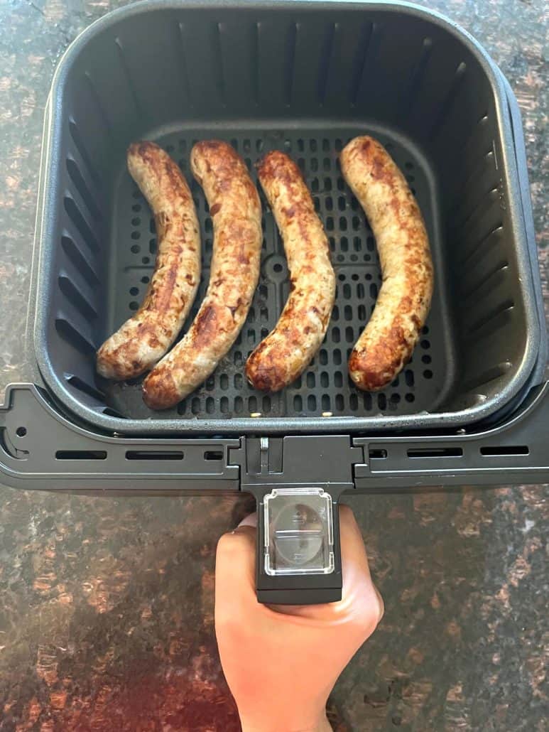 Greek sausages being shown in an air fryer by Melanie from MelanieCooks.com.