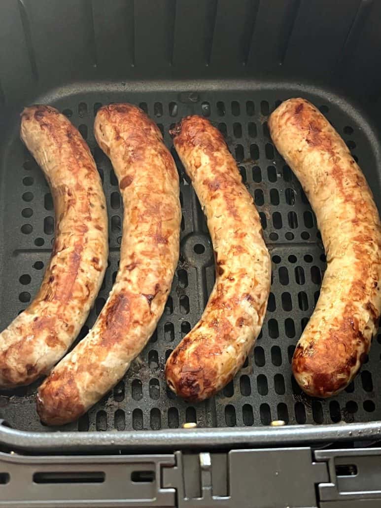 Close-up of four Greek sausages inside an air fryer basket.