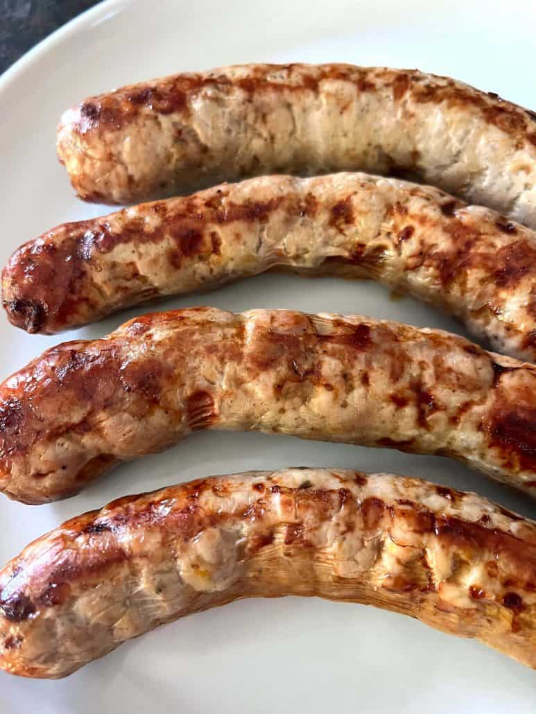 Top view of four pieces of Greek sausage on a white plate.