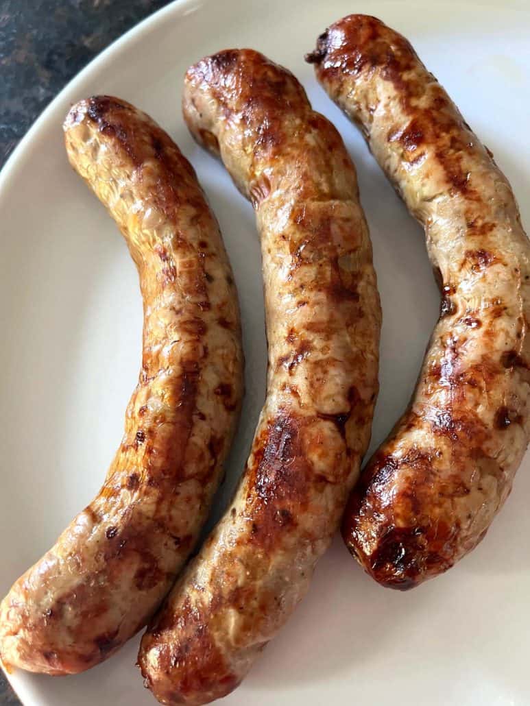 Three pieces of Greek sausage on a white plate.