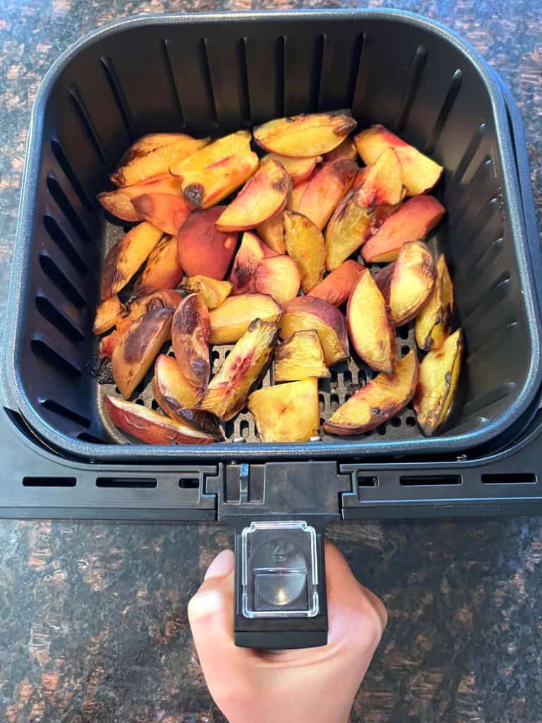 These freshly roasted peaches in an air fryer basket. Perfectly caramelized, healthy snack or dessert.