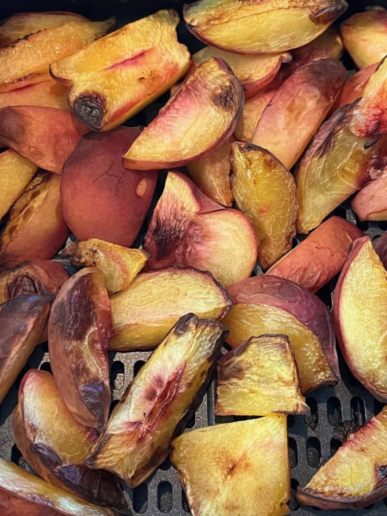 Close-up of roasted peach slices in an air fryer, showing their naturally sweet snack, made with no added sugar.