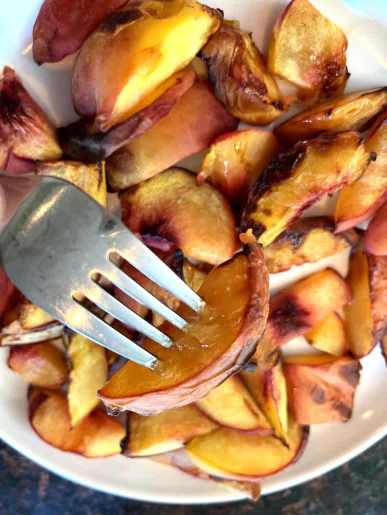 Closed-up of fork lifting a slice of roasted peach. A naturally sweet and healthy snack. ready to be serve.