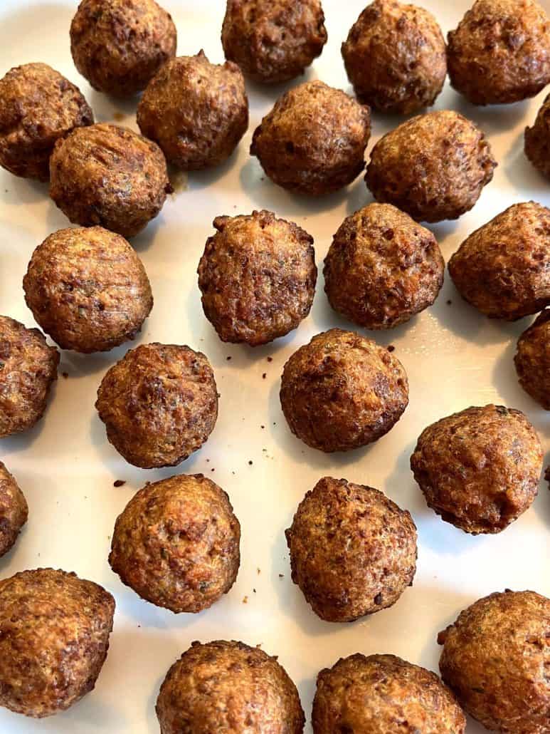 Close-up of freshly cooked golden-brown vegan meatballs arranged on a white plate.