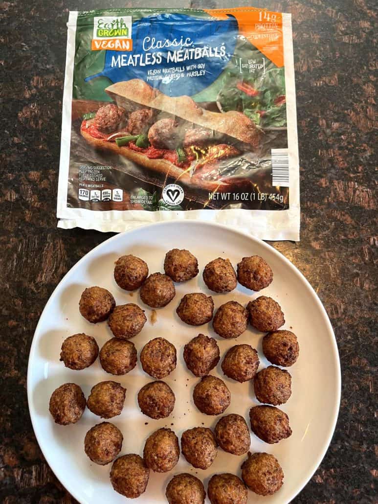 Final result after air frying. A plate of freshly cooked vegan meatballs placed next to the packaging of Earth Grown Classic Vegan Meatless Meatballs,