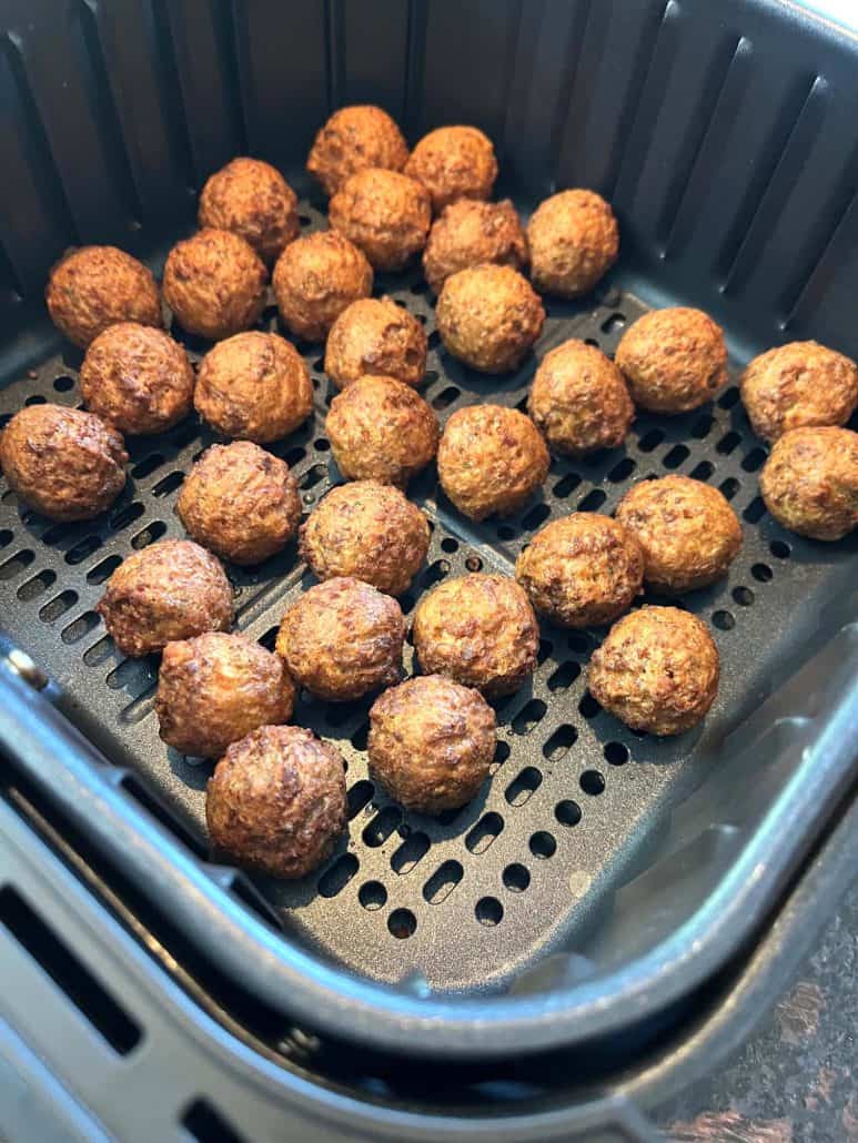 Freshly cooked crispy, golden-brown vegan meatballs in an air fryer basket, 