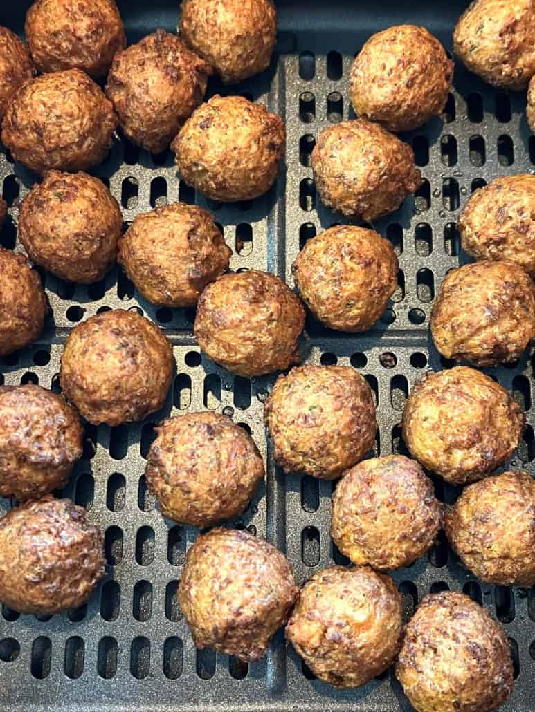 Close-up view of perfectly golden-brown vegan meatballs inside an air fryer basket, freshly cooked and ready to serve.