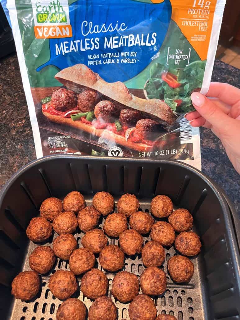 A package of Earth Grown Classic Vegan Meatless Meatballs above a basket of perfectly cooked vegan meatballs in an air fryer.