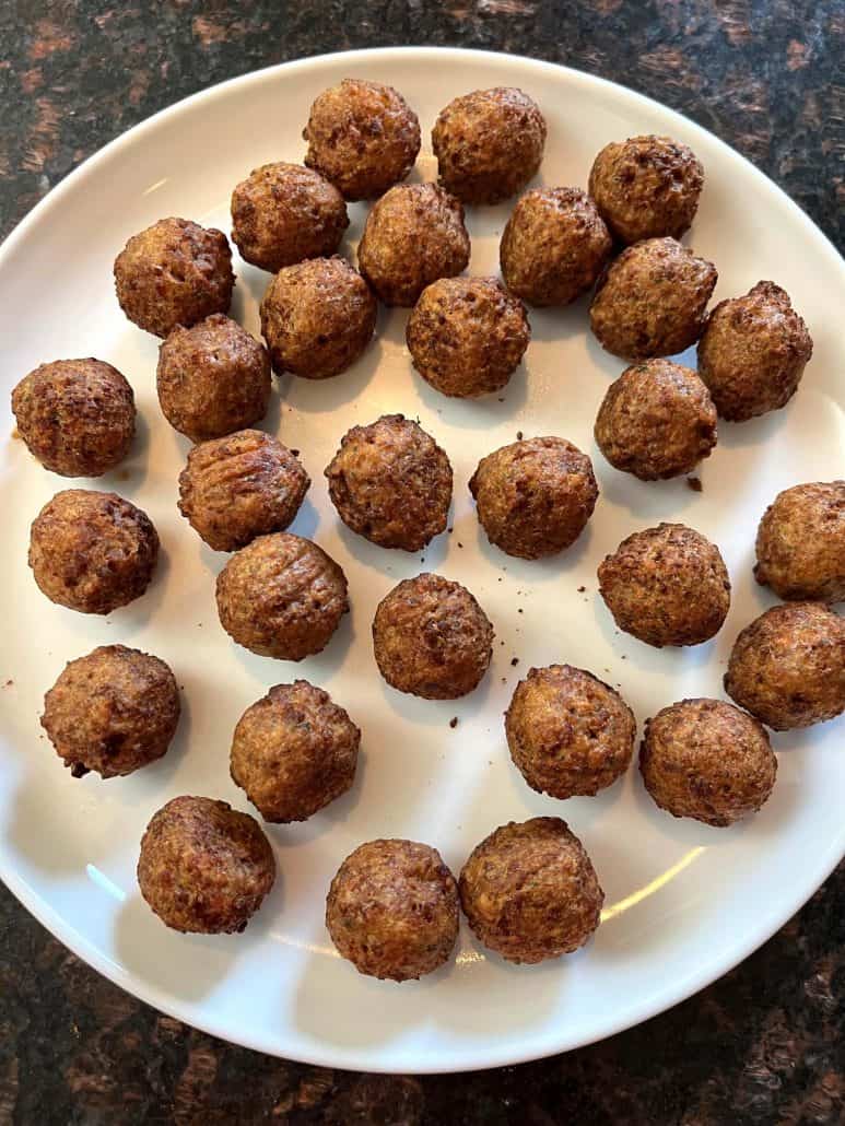 A white plate filled with freshly cooked, golden-brown vegan meatballs, ready to be served.