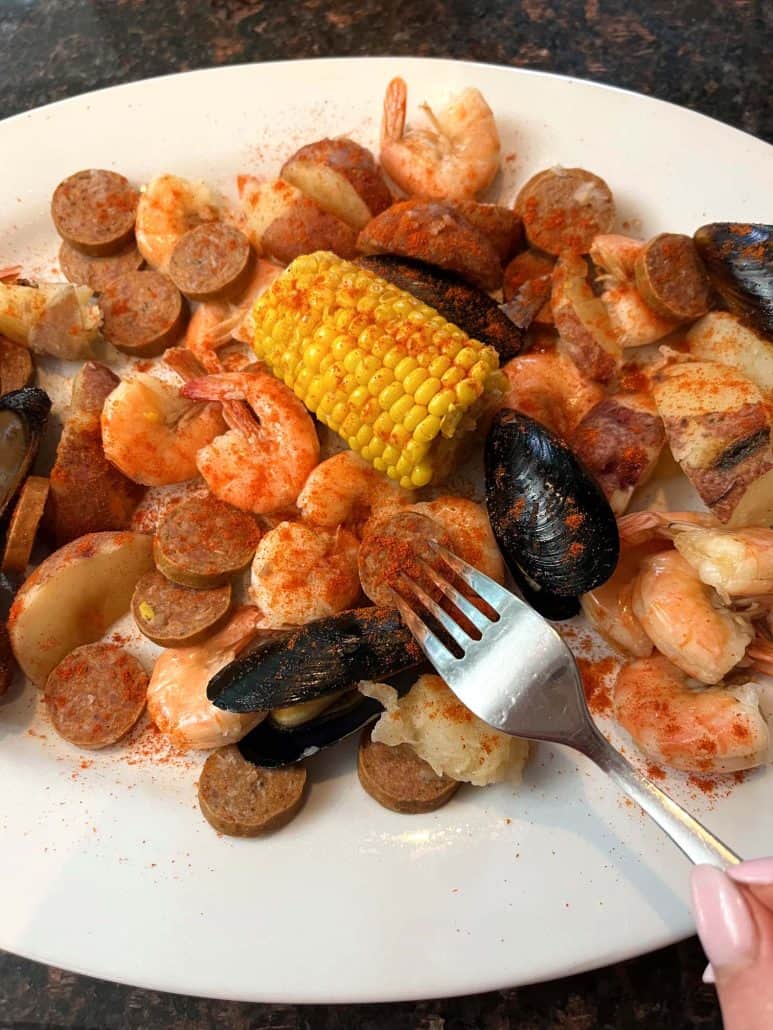 A fork is poised to pick up a piece of mussel, showing the dish, made from Aldi's Frozen Seafood Boil, is ready to enjoy.