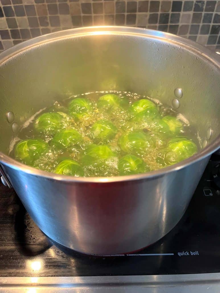 A pot of Brussels sprouts boiling on the stovetop, illustrating the process of cooking them.