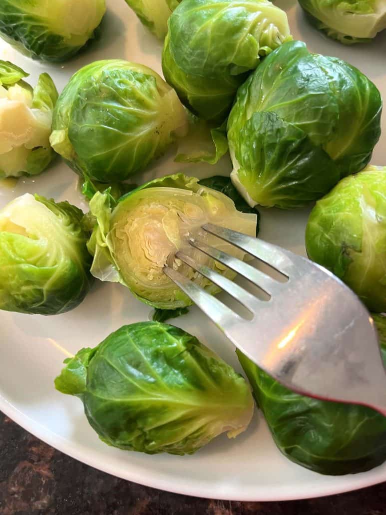 Showcasing the tender inside and bright green outer leaves of boiled Brussels sprout on a plate.