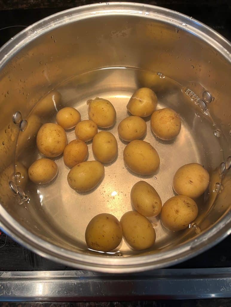 Small potatoes boiling in a pot of water on the stove, showing the cooking process from the Boiled Small Potatoes recipe.