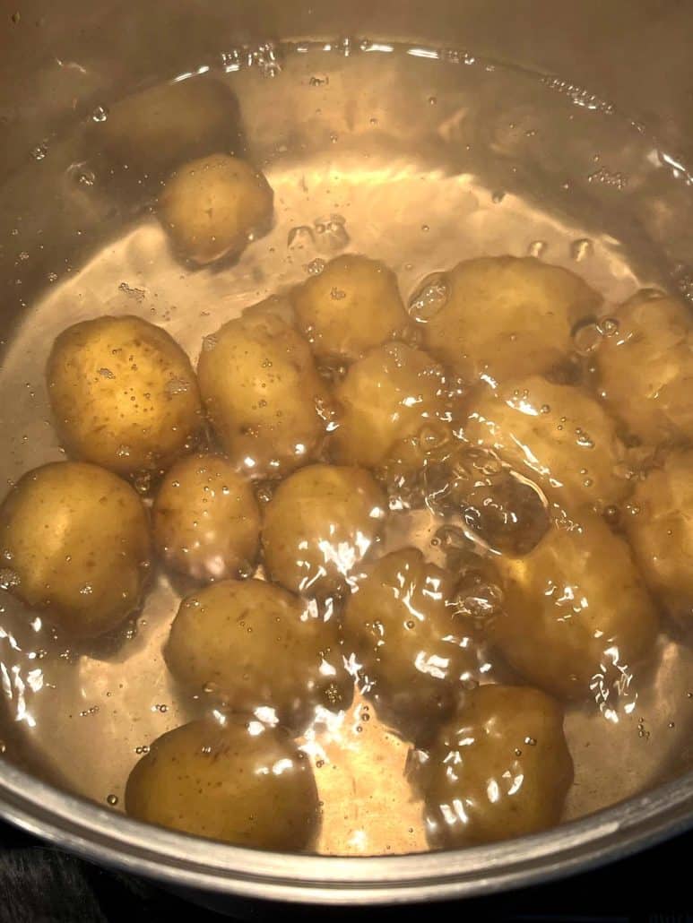 Close up image of small potatoes boiling in water for 20 minutes. 