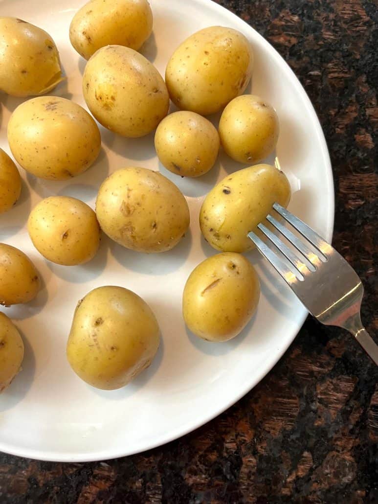 Ready to be eaten boiled small potatoes on a white plate.