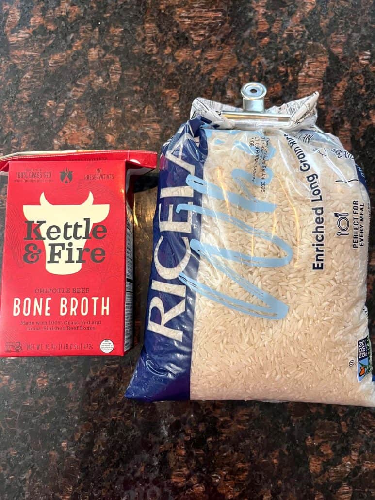 A package of Kettle & Fire Chipotle Beef Bone Broth next to a bag of long grain white rice, showcasing the main ingredients used in the bone broth rice recipe for added flavor and protein.