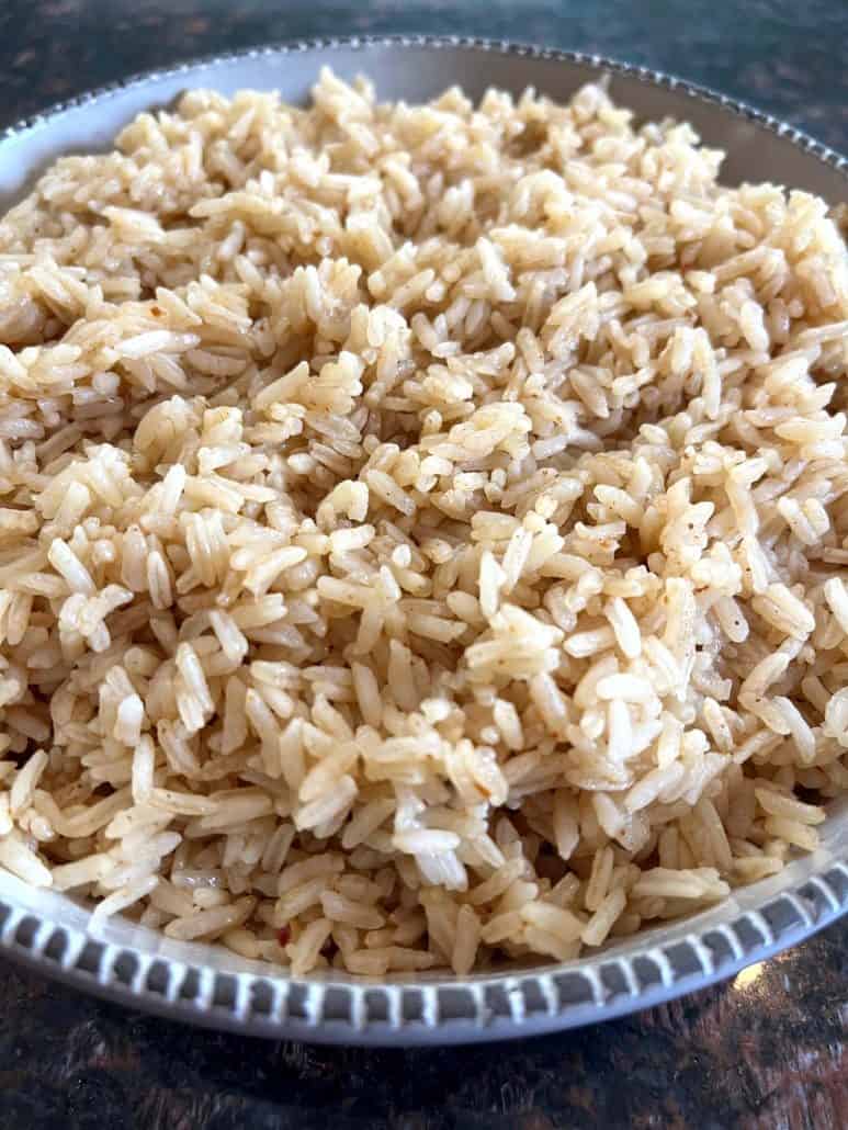 A side angle view of a bowl filled with fluffy, well-cooked bone broth rice, showing the individual grains and light texture.