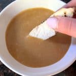 A hand dipping a piece of chicken into a bowl of smooth, homemade Chick-Fil-A sauce, showcasing the creamy texture of this easy copycat recipe.