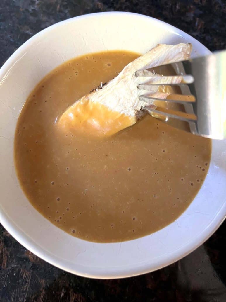 A fork holding a piece of chicken dipped into homemade Chick-Fil-A sauce.