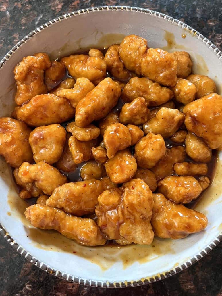 A bowl filled with crispy General Tso’s chicken coated in a sticky.