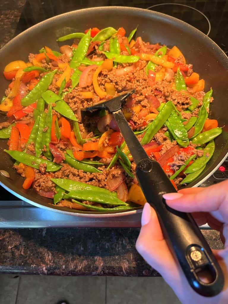 Melanie from melaniecooks.com sautéing mixed vegetables with ground beef.