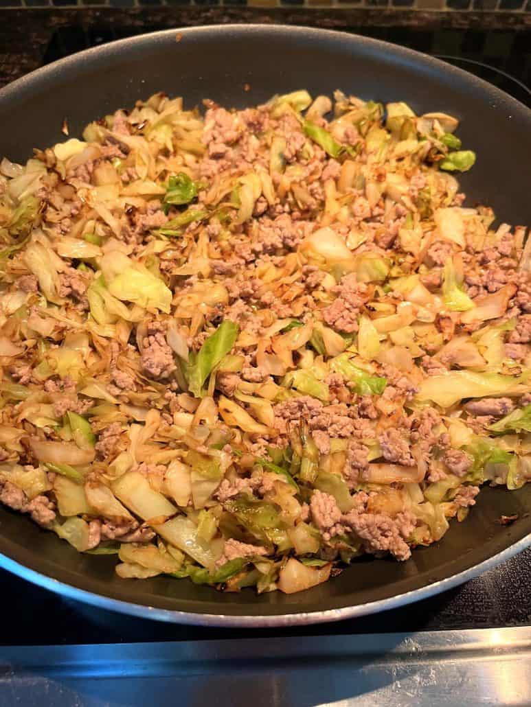 A pan filled with cooked ground turkey and sautéed cabbage, showcasing a healthy and low-carb meal that's easy to prepare. 