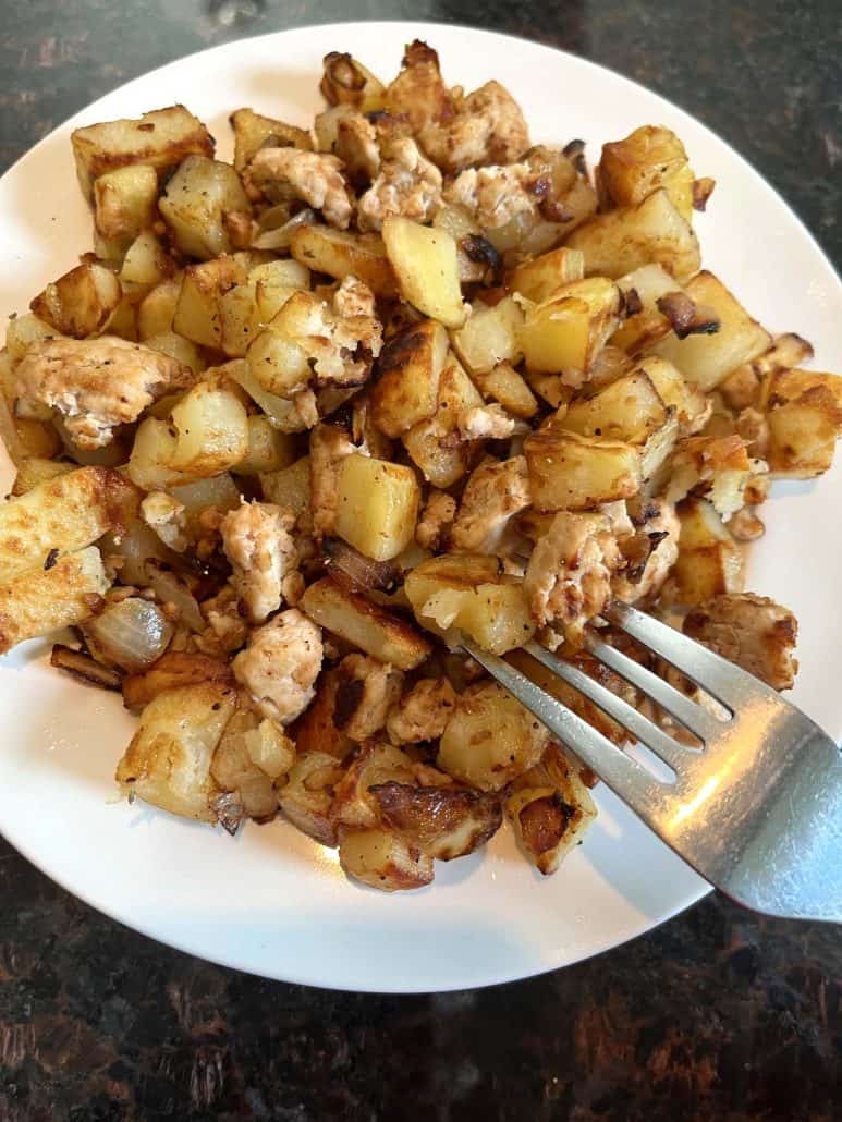 A plate of golden-brown diced potatoes and ground turkey.