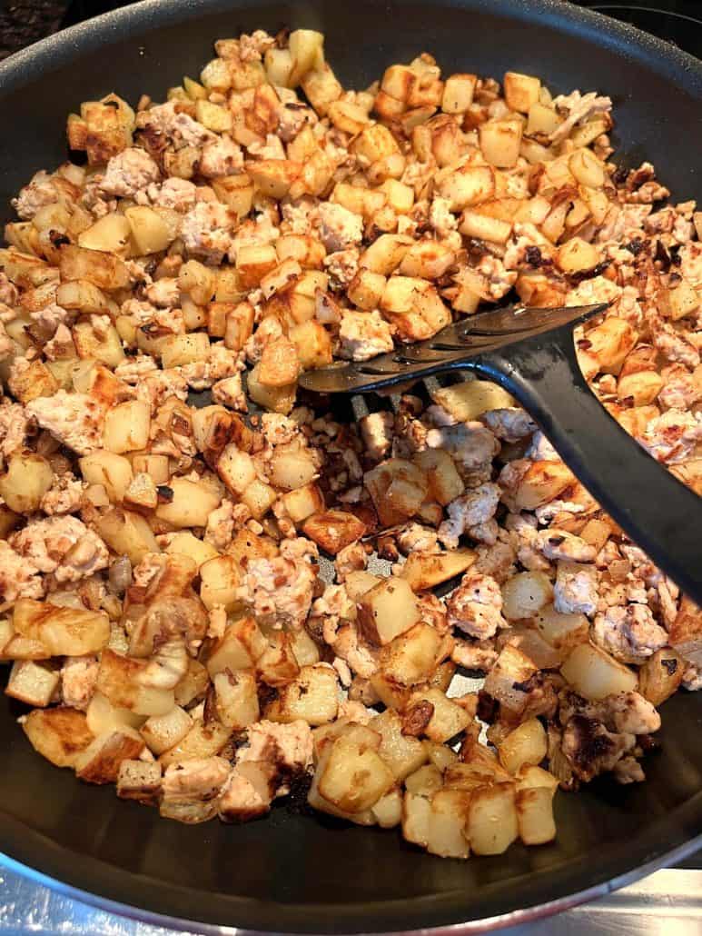 Diced potatoes and ground turkey, being stirred with a spatula