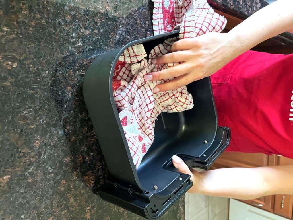 Drying the outer basket of a Cosori air fryer with a soft towel.