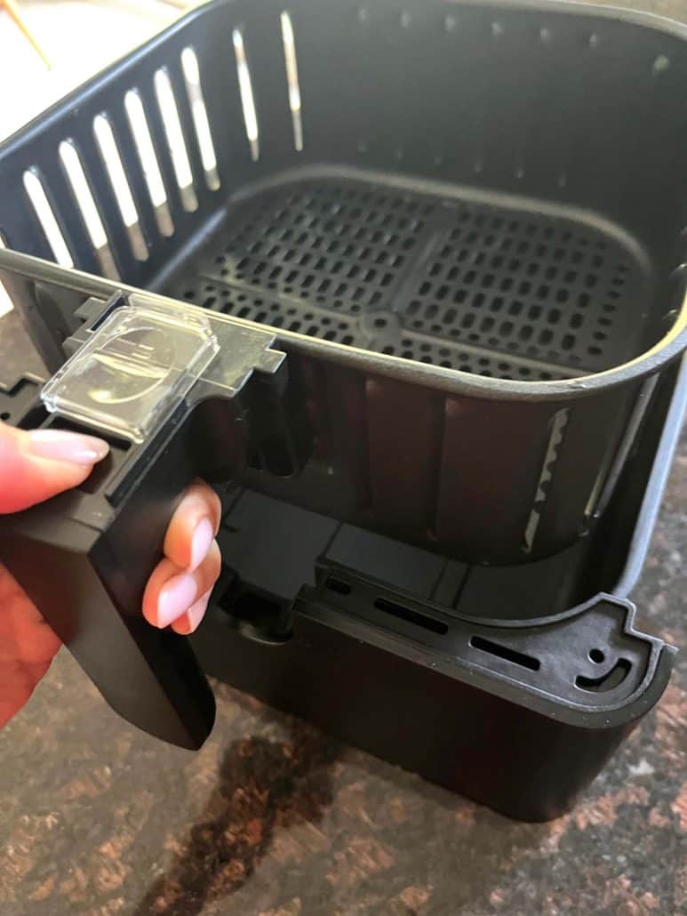 Reassembling the clean and dry inner and outer baskets of a Cosori air fryer.