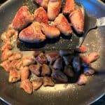 Golden-browned chicken hearts lifted on a spatula from a frying pan, showing their crispy exterior after being sautéed to perfection.