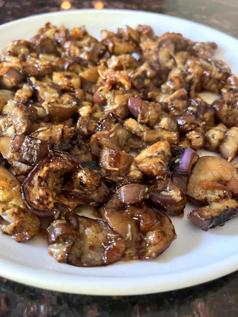 A plate of pan-fried Chinese eggplant coated in a savory garlic sauce, showing caramelized pieces with a glossy finish, ready to be served as a flavorful dish.