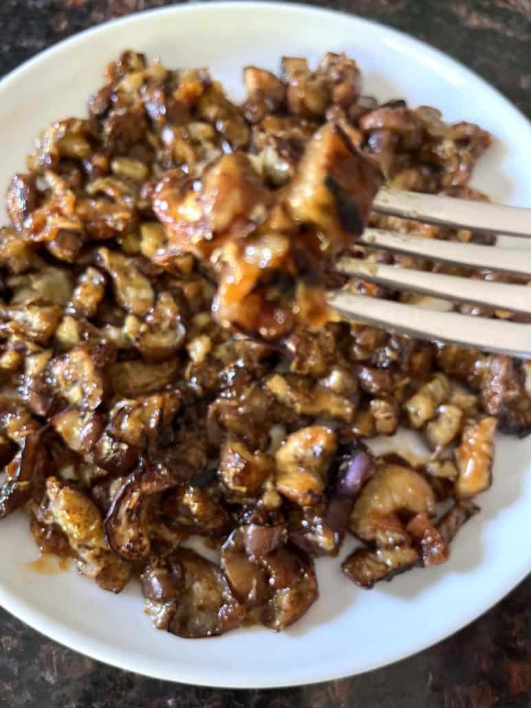 A close-up of a plate of pan-fried Chinese eggplant with garlic sauce, showing tender, caramelized pieces of eggplant coated in a glossy, flavorful sauce, highlighting the dish's delicious texture and rich flavors.