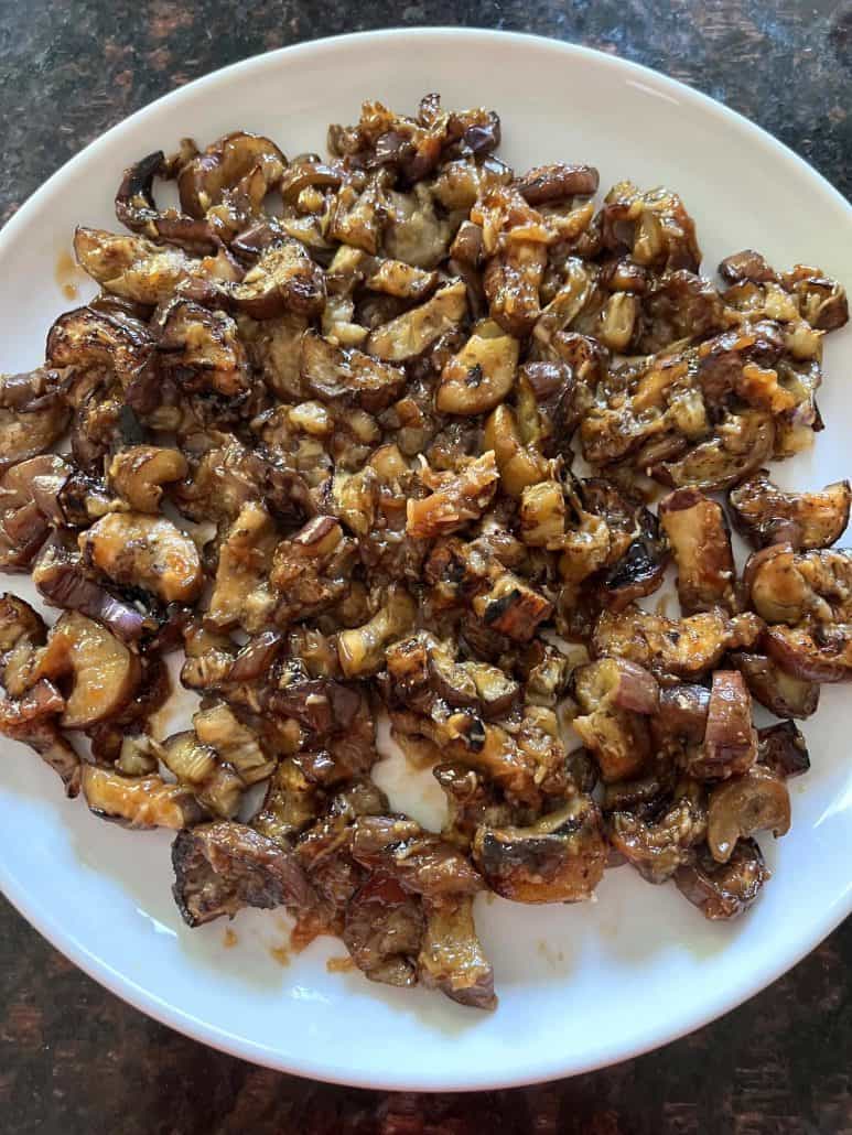 A white plate filled with pan-fried Chinese eggplant in garlic sauce, displaying a generous serving of tender, caramelized eggplant pieces evenly coated in a rich, flavorful sauce.