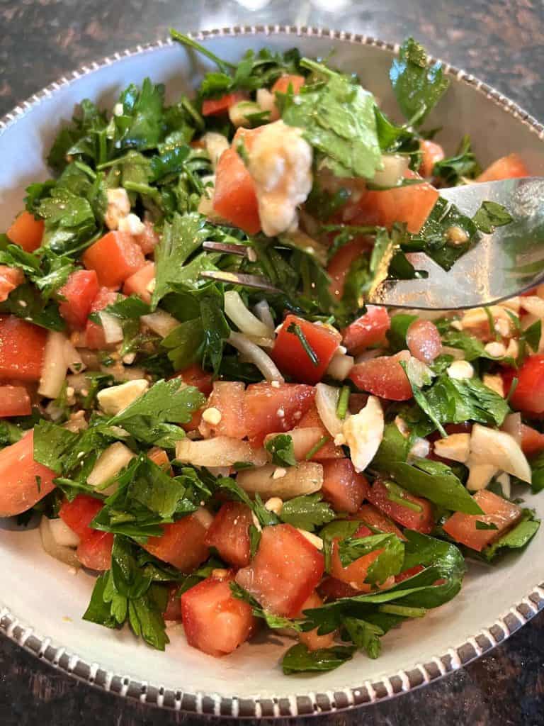 A fork scooping up a portion of a fresh parsley salad.