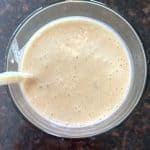 A top-down view of a creamy Peanut Butter Banana Smoothie in a glass with a yellow straw.