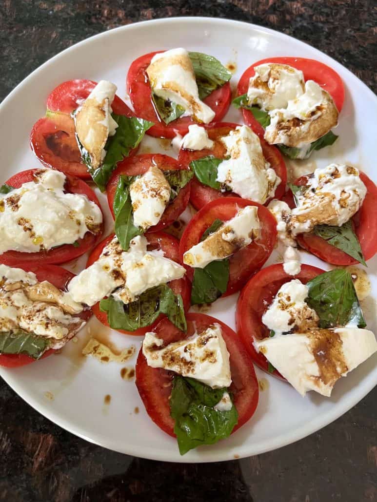 Zoomed-in view of a tomato burrata salad on a plate.