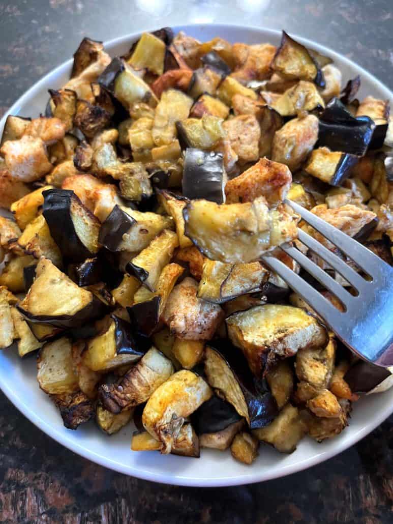 Close-up of a fork holding a piece of air-fried chicken and eggplant from a plate, highlighting the crispy and tender results of the Air Fryer Chicken and Eggplant recipe.