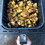 Hand holding the air fryer basket filled with golden-brown chicken and eggplant, showcasing the crispy result of the Air Fryer Chicken and Eggplant recipe.