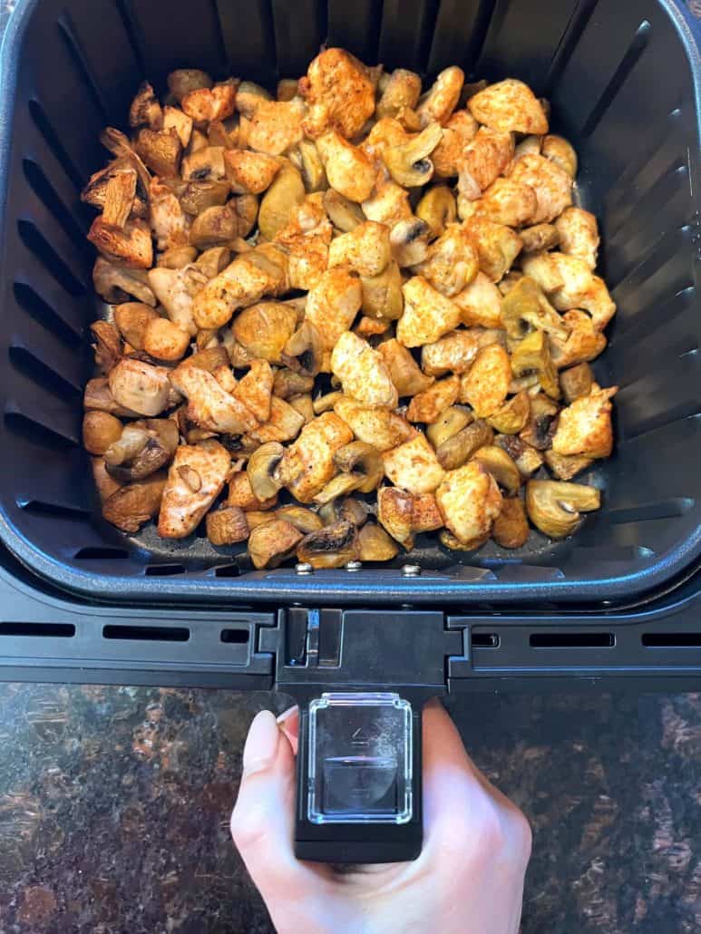 Cooked chicken and mushrooms in an air fryer basket.Showing the golden brown Air Fryer Chicken and Mushrooms recipe.