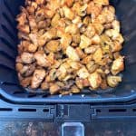 Air fryer basket filled with perfectly cooked, seasoned chicken and mushrooms.