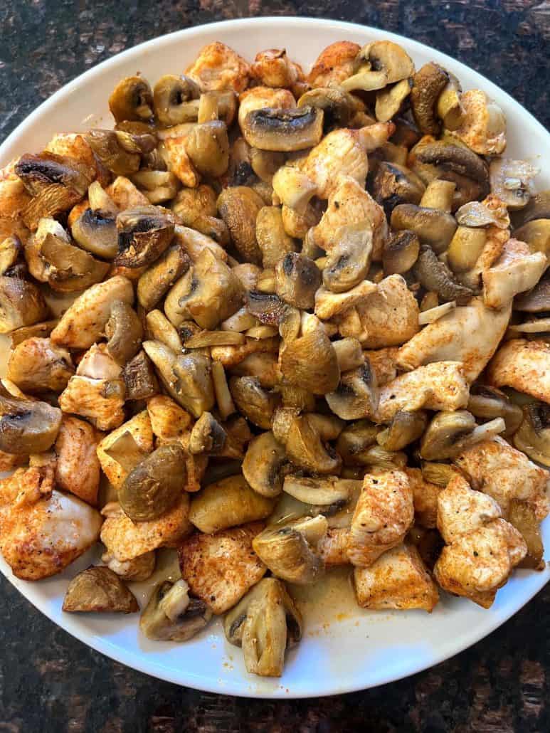 Top view of a plate filled with juicy chicken and tender mushrooms.