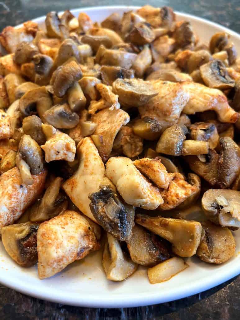 Plate of perfectly cooked chicken and mushrooms and well-seasoned bites from the easy Air Fryer Chicken and Mushrooms recipe.