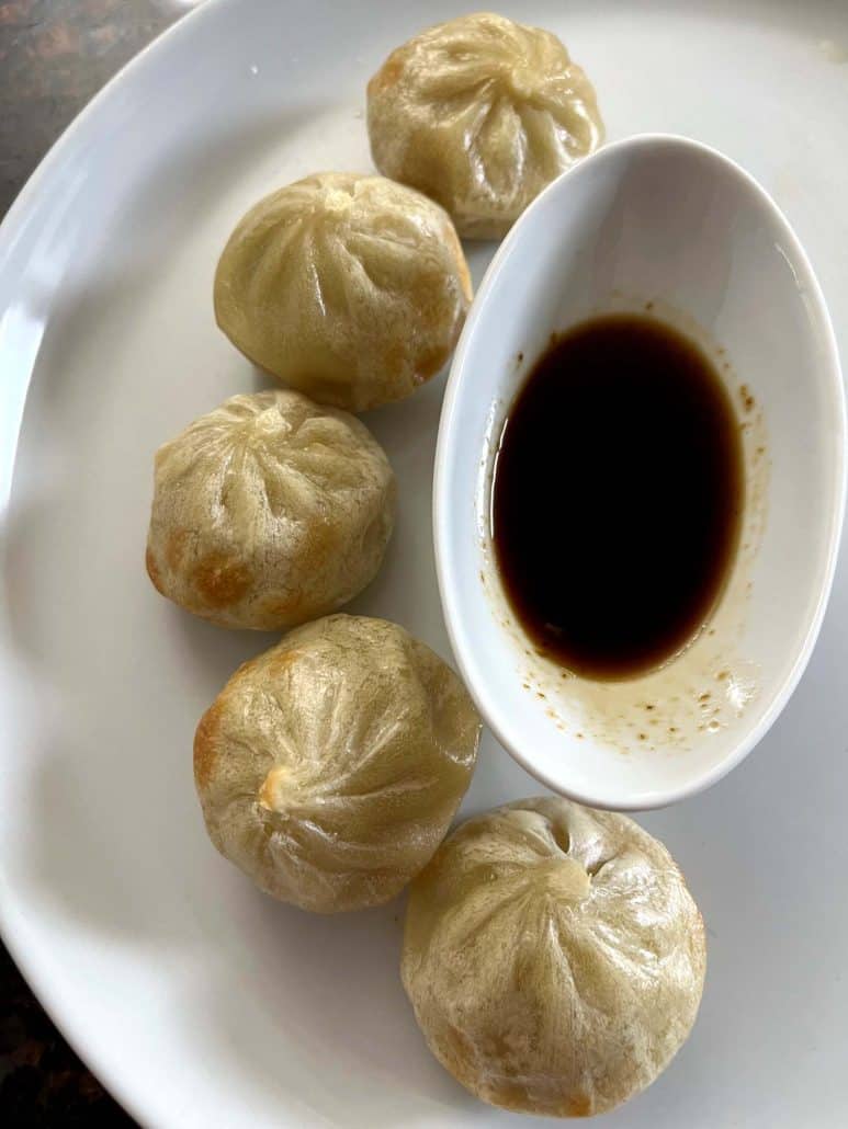 Plate of air-fried Bibigo dumplings served with a bowl of soy dipping sauce, ready to enjoy as a delicious appetizer or snack.